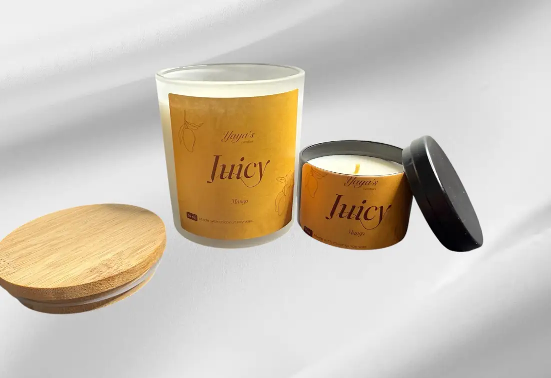 Two scented candles labeled "Juicy Mango" with a bamboo lid and a metal tin, showcasing their vibrant yellow packaging.